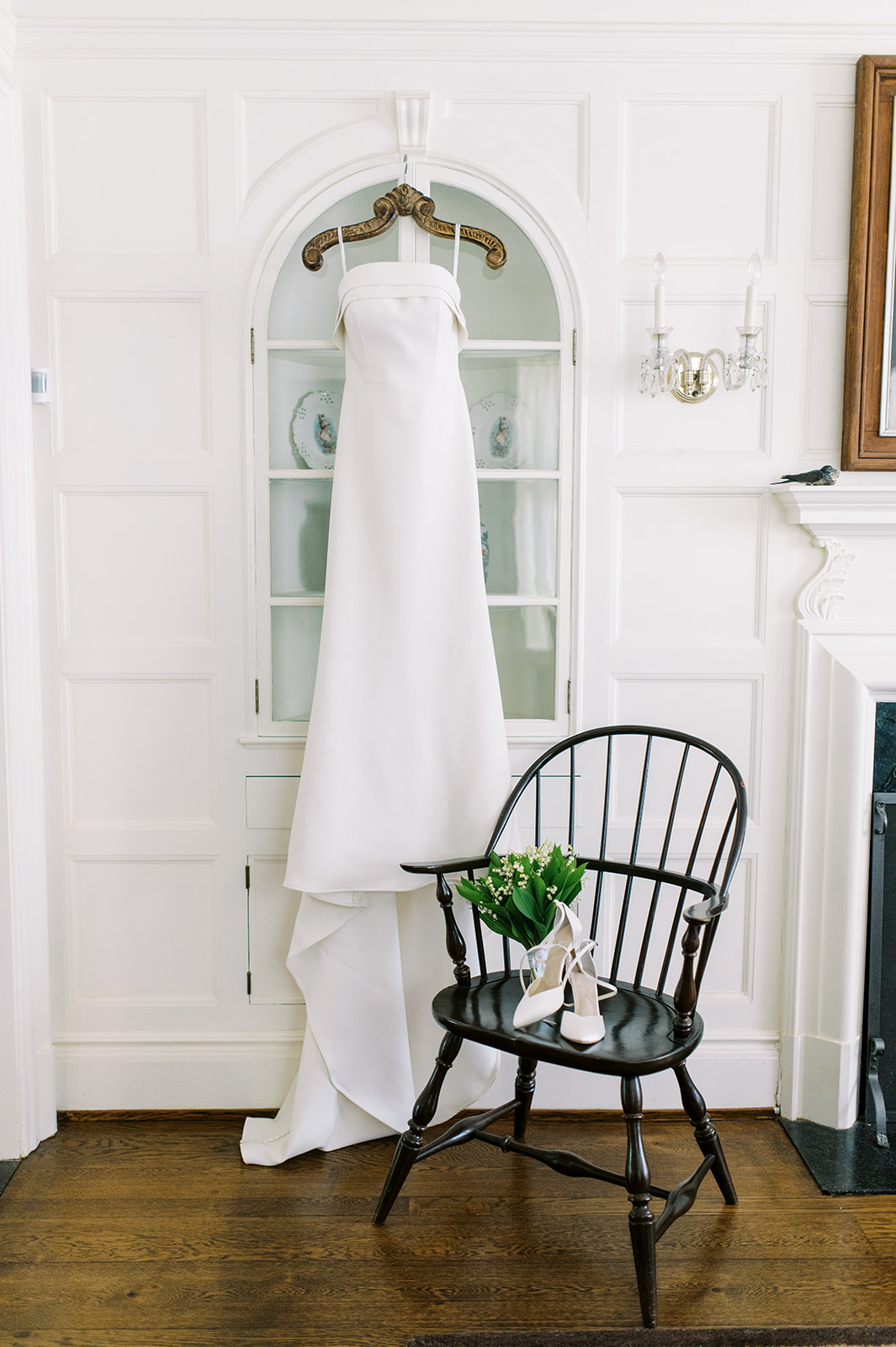 modern wedding gown hangs on arched door of historic home for preppy Grandmillennial Backyard Spring Afternoon Wedding
