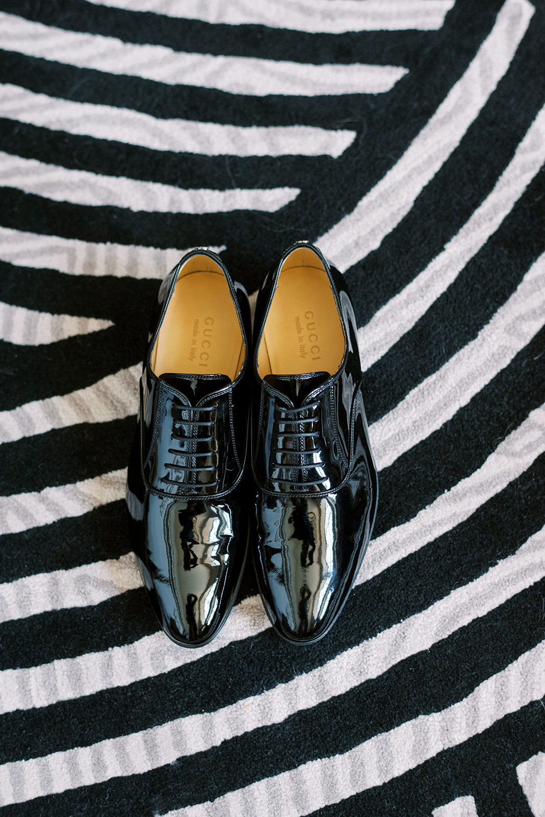 Groom's Gucci shoes against a black and white striped carpet