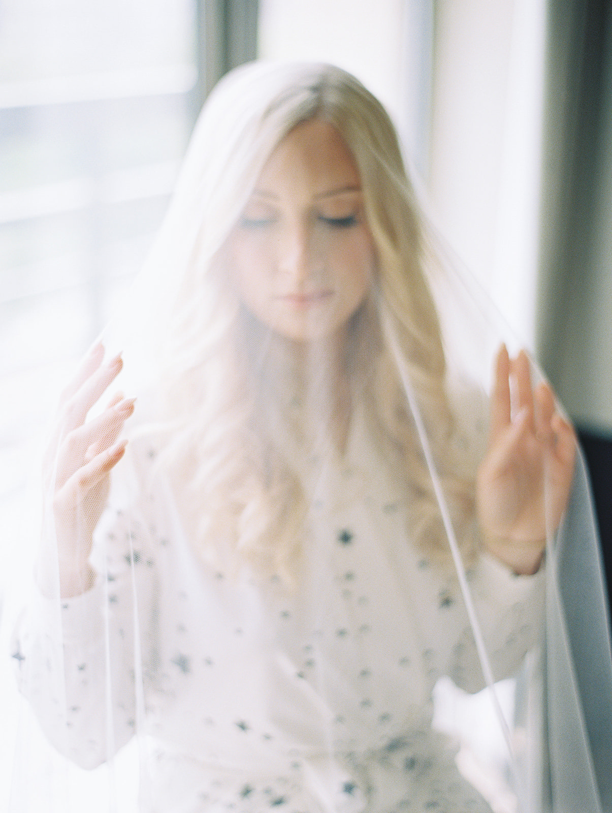 Bride in her getting-ready robe with her veil draped overhead