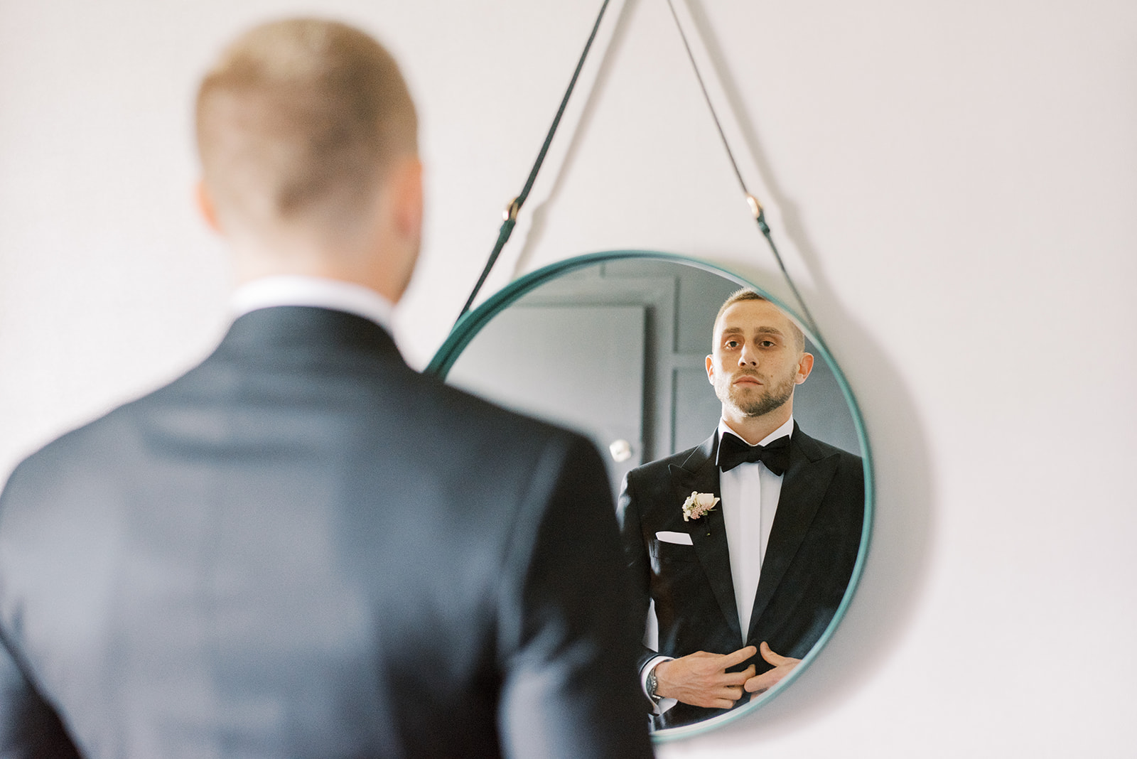 Groom getting ready at the Renaissance Hotel in Philadelphia looking in a round mirror hanging on wall