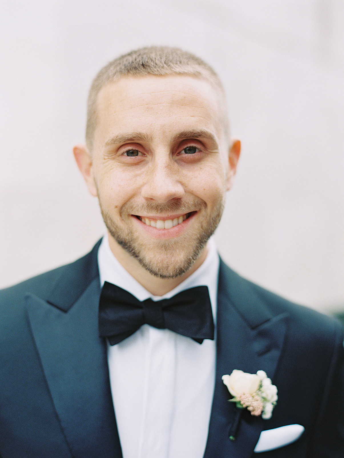 Groom smiling at the camera with black bow tie