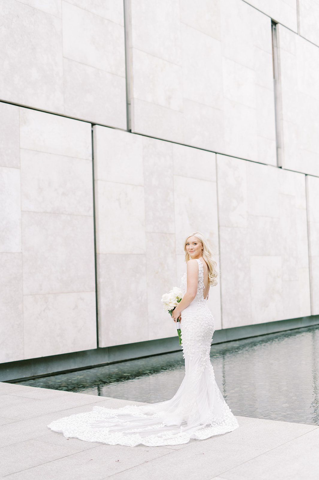 bride in wedding gown against marble wall of Barnes Foundation Philadelohia