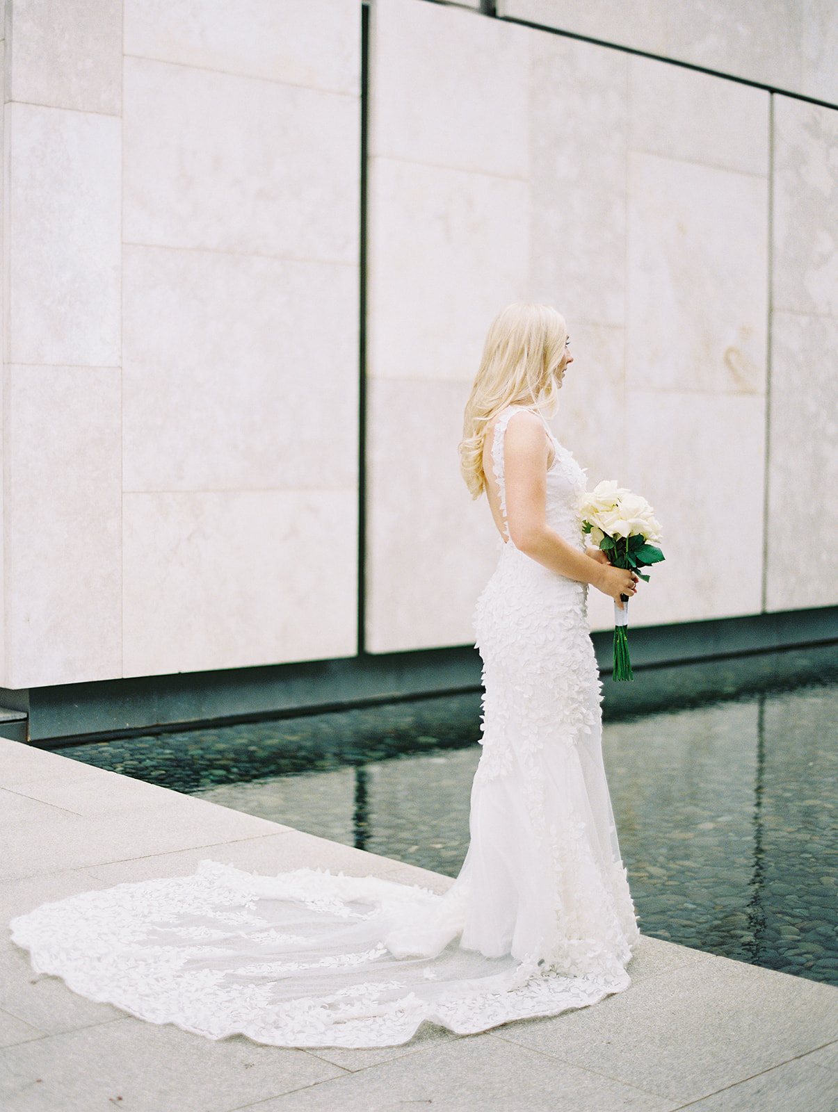 full body portrait of a bride at the Barnes Foundation holding a bouquet of white long-stem roses