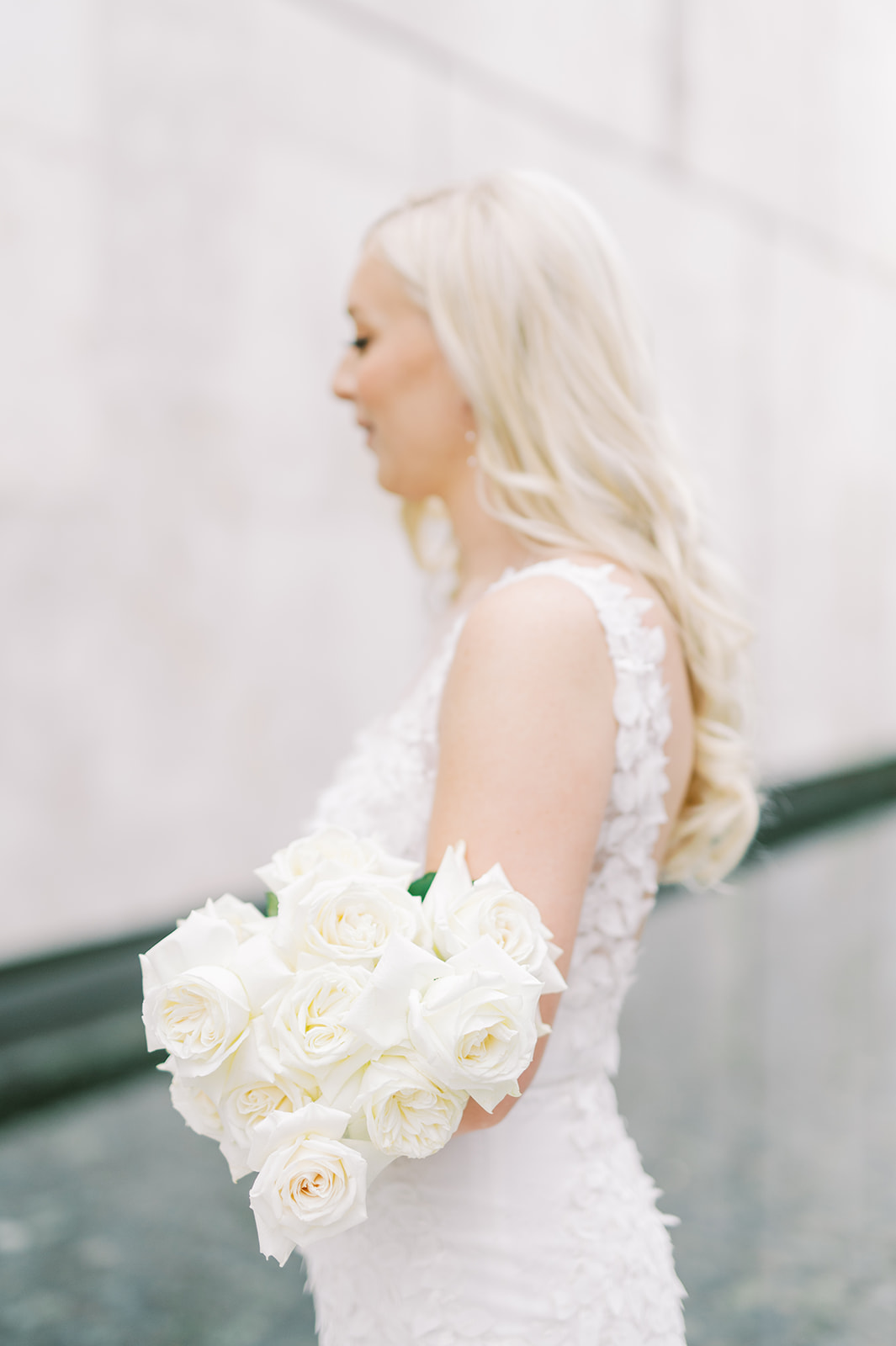 Bride looking away from camera with bouquet of white roses
