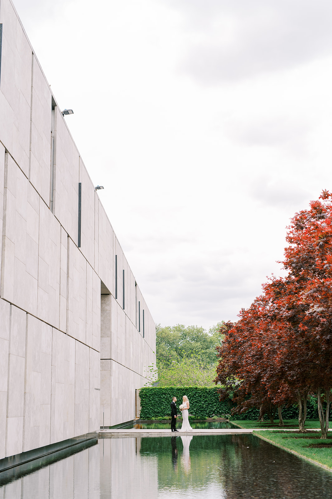 Bride and groom on the walkway leading to the Barnes Foundation and the reflecting pool with a red Japanese Maple Tree 