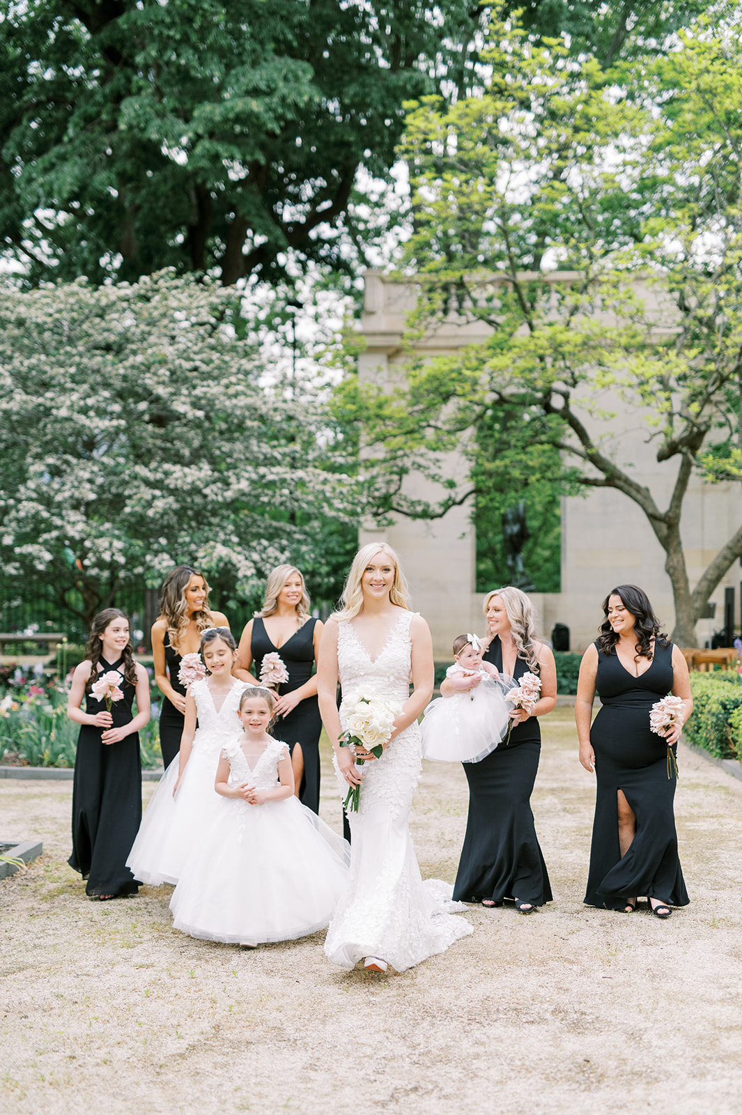 bridesmaids in black walking with a bride in a white dress and flower girls in white dresses at the Rodin Museum