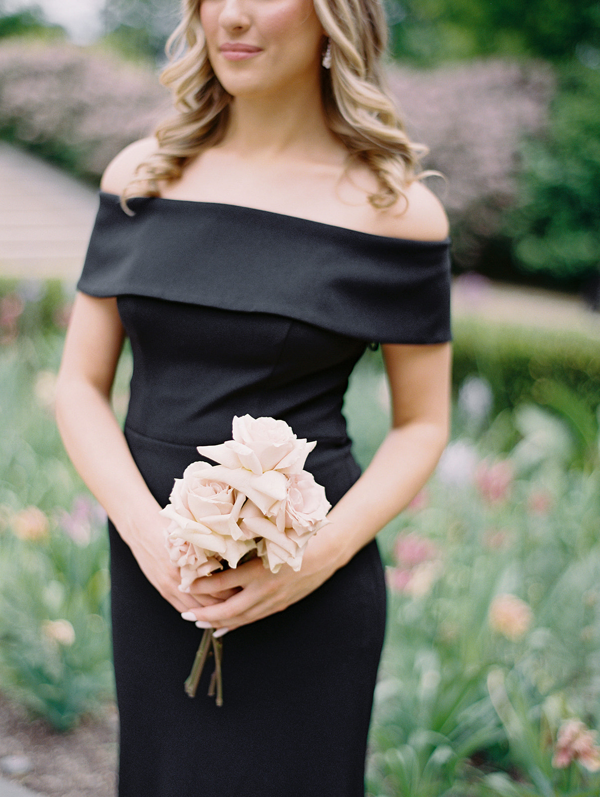 bridesmaid in black dress at the Rodin Museum holding a small bouquet of blush roses
