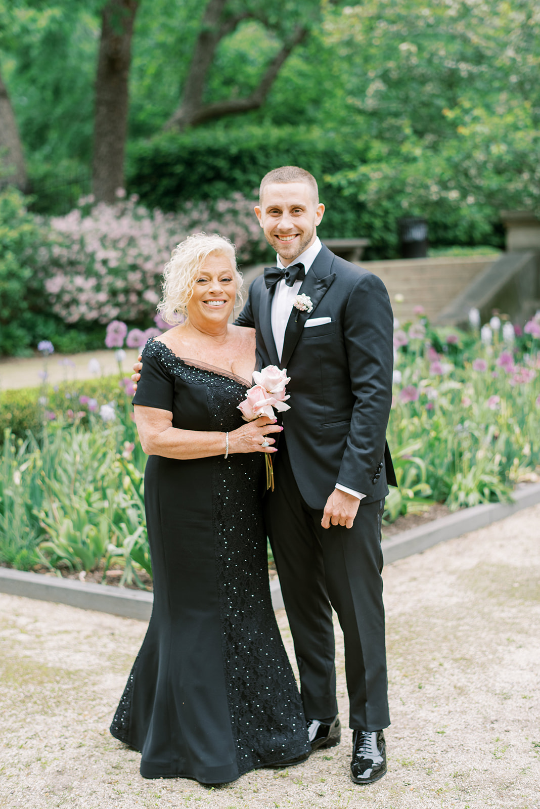 Groom and his mother wearing a black dress and holding blush roses at the Rodin Museum