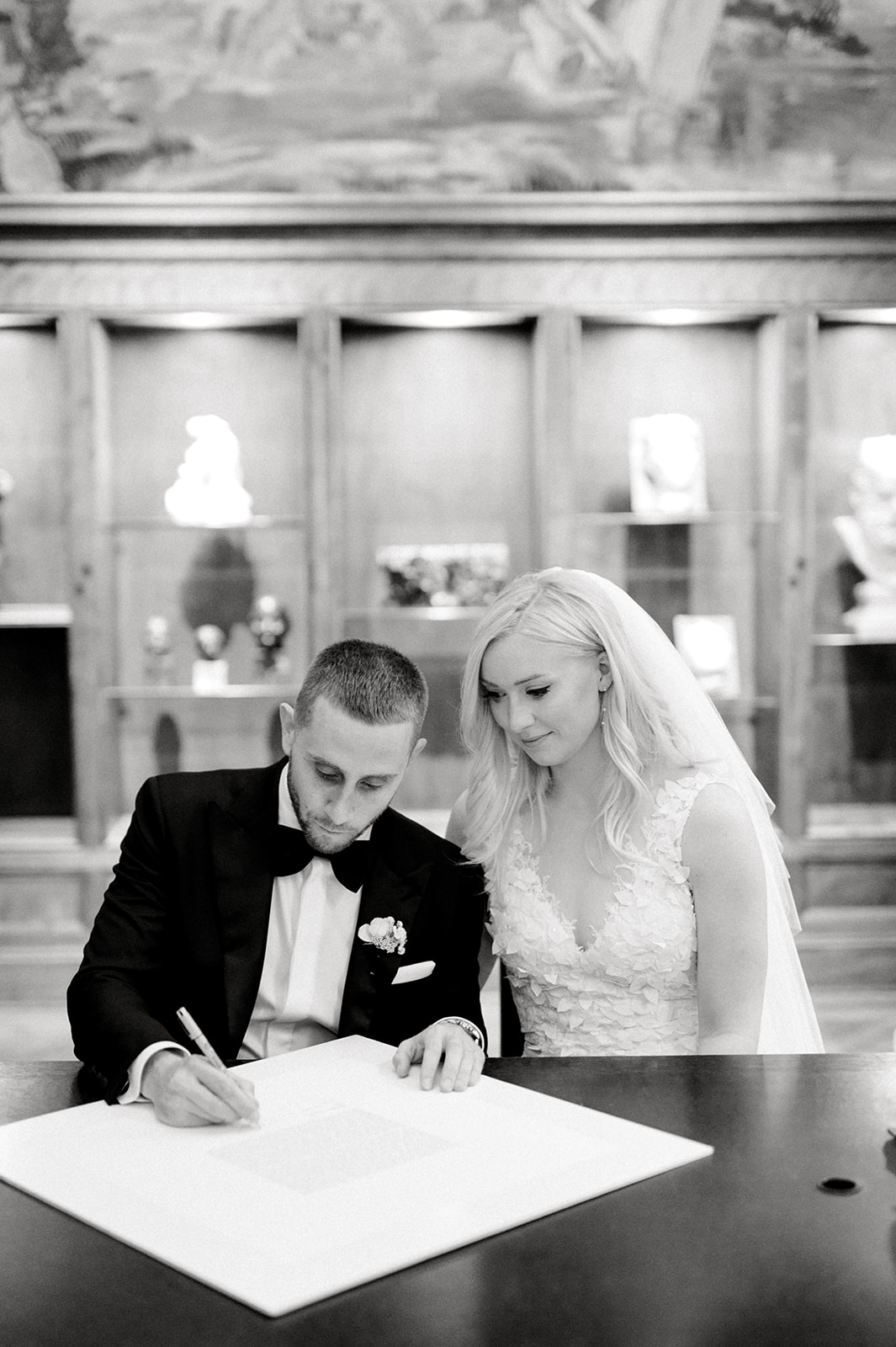 black and white photo of bride and groom signing ketubah indoors at Rodin Museum