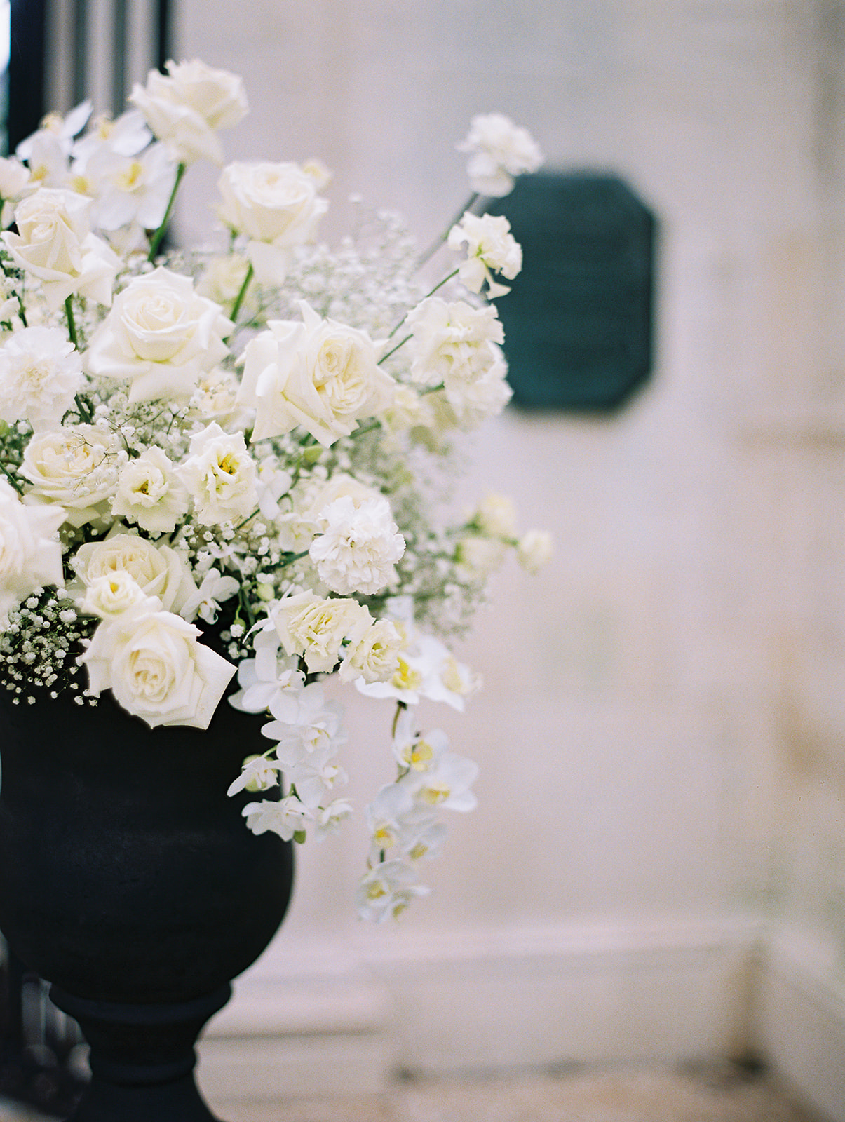 Closeup shot of ceremony arrangement in a black vase with white roses and white babies breath at Rodin Museum