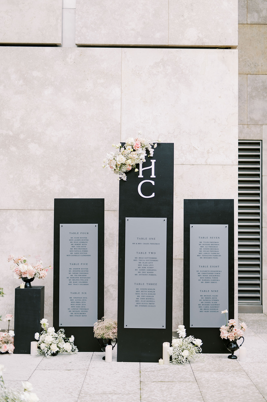 modern black seating chart pillars adorned with white and blush florals
