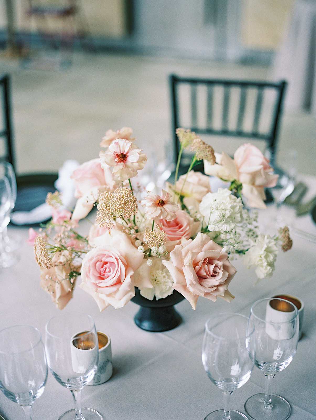 modern wedding centerpiece with black compote with roses, ranunculus, and lisianthus in white and blush