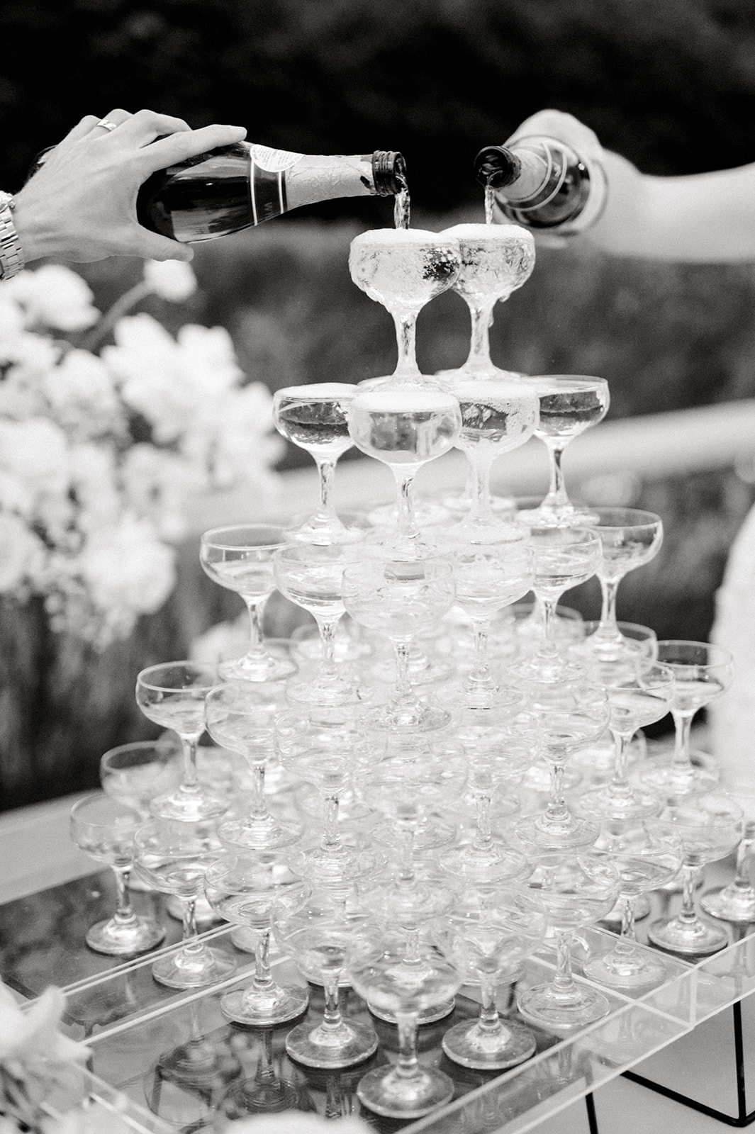 black and white image of a couple pouring champagne into a champagne tower