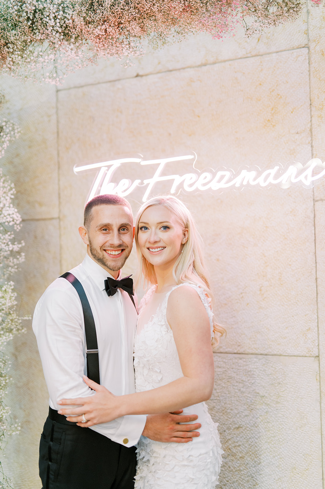 bride and groom smiling at the camera with neon sign in the background