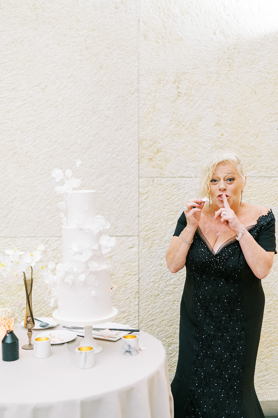 mother of groom taking a sneaky bite out of the wedding cake