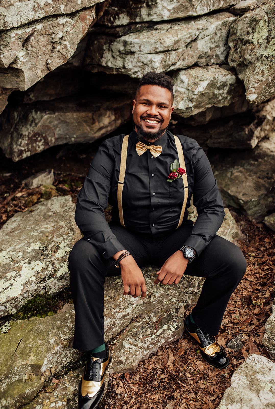 groom in black with gold suspenders and bow tie