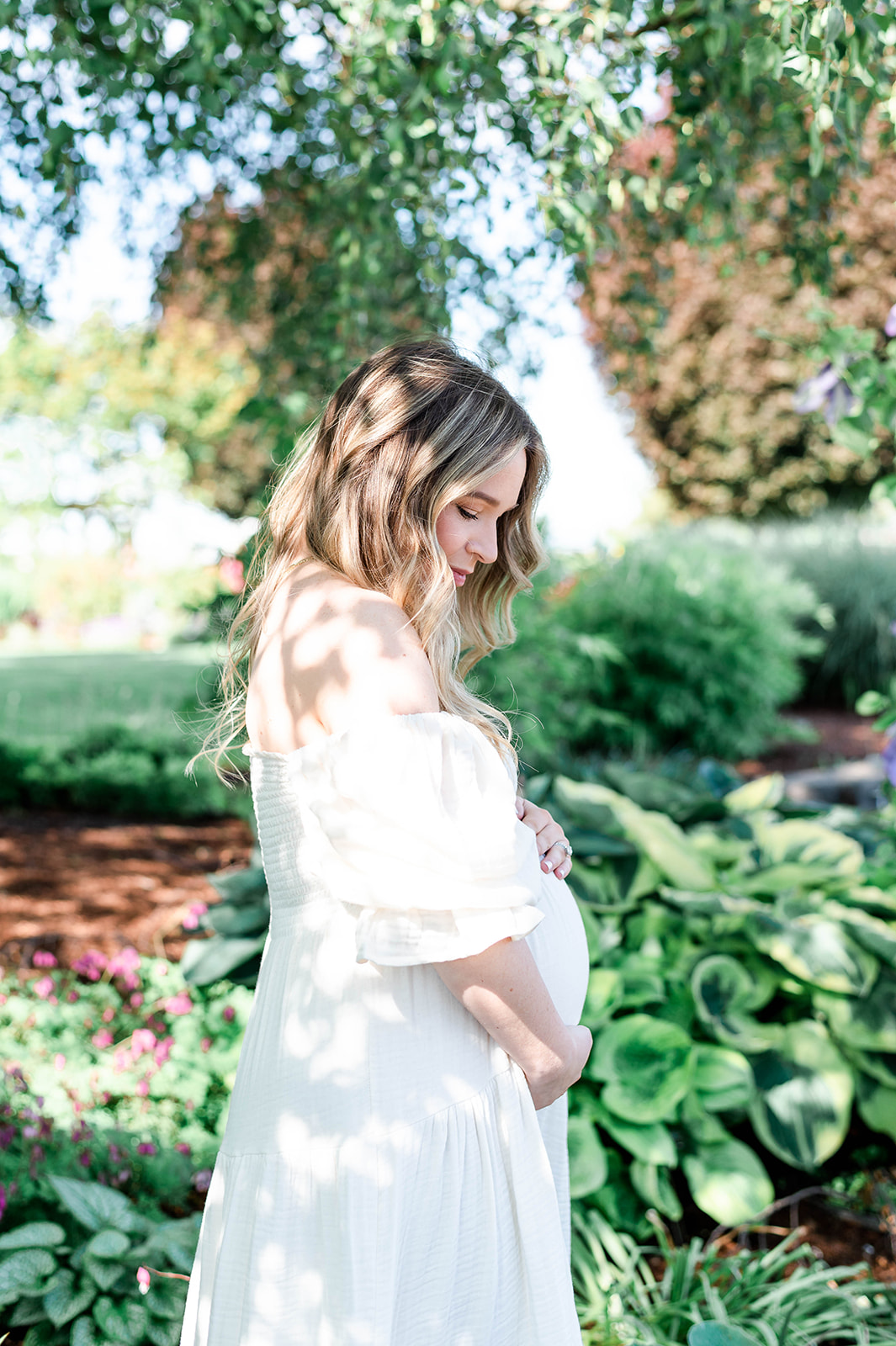 glowing pregnant woman wearing a white dress at Adelman Peony Gardens