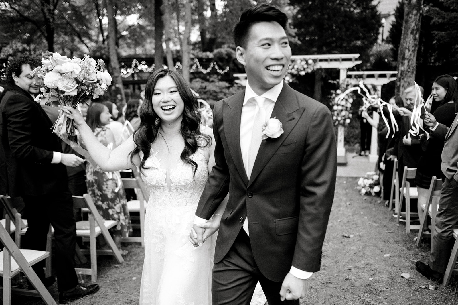 black and white photo of bride and groom smiling as they exit their wedding ceremony