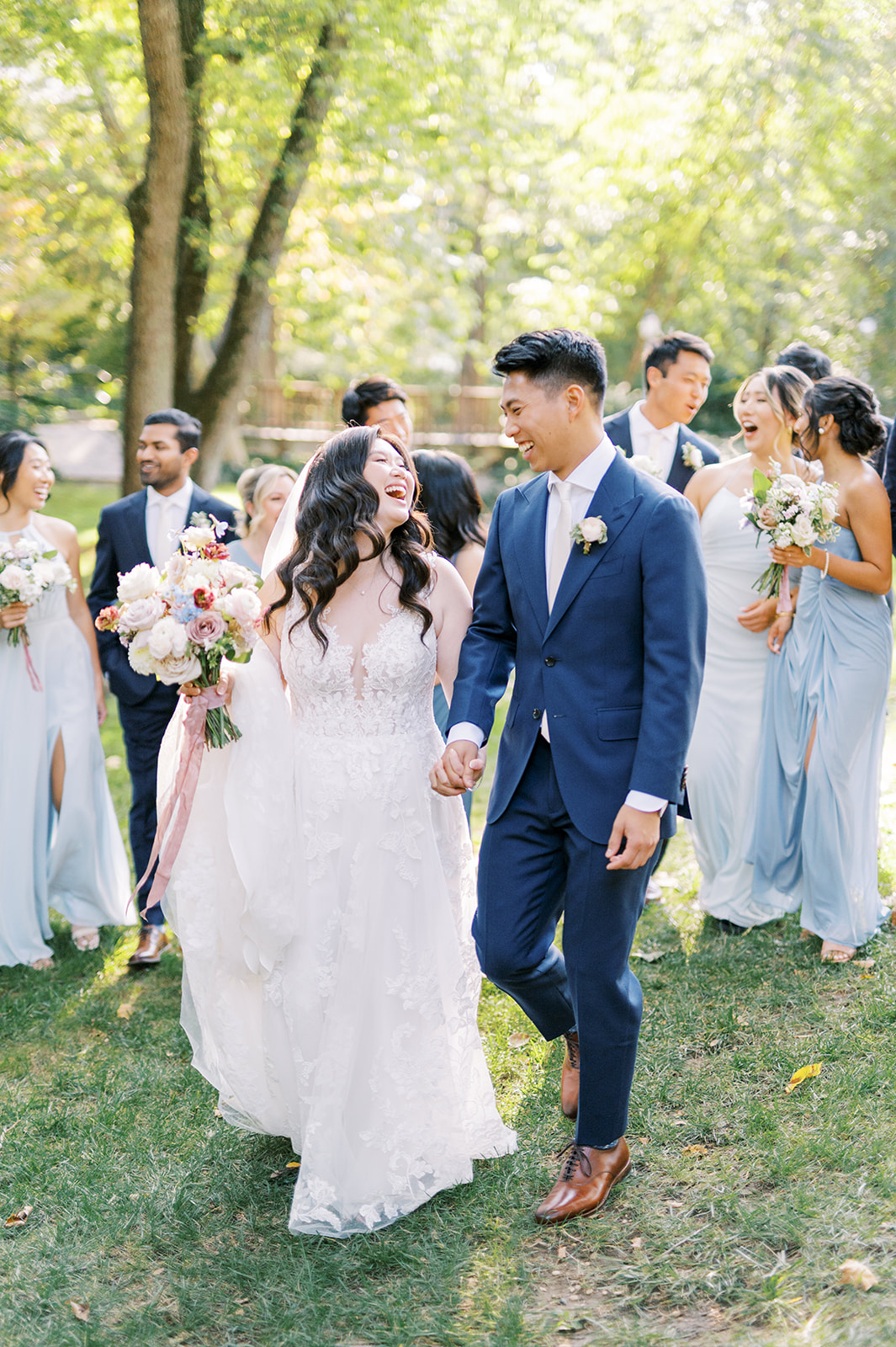 bride and groom walk hand in hand with bridal party on lawn of pomme Radnor