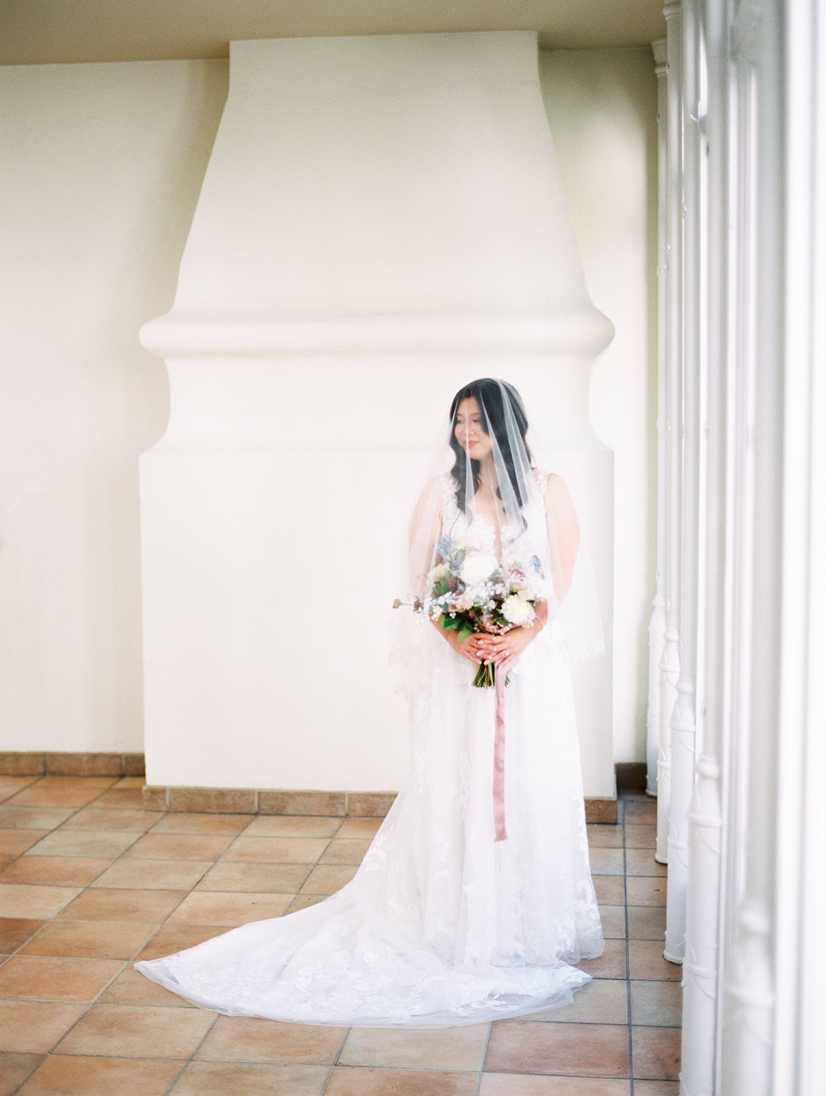 bride with veil draped over her in white room at pomme in radnor, pa