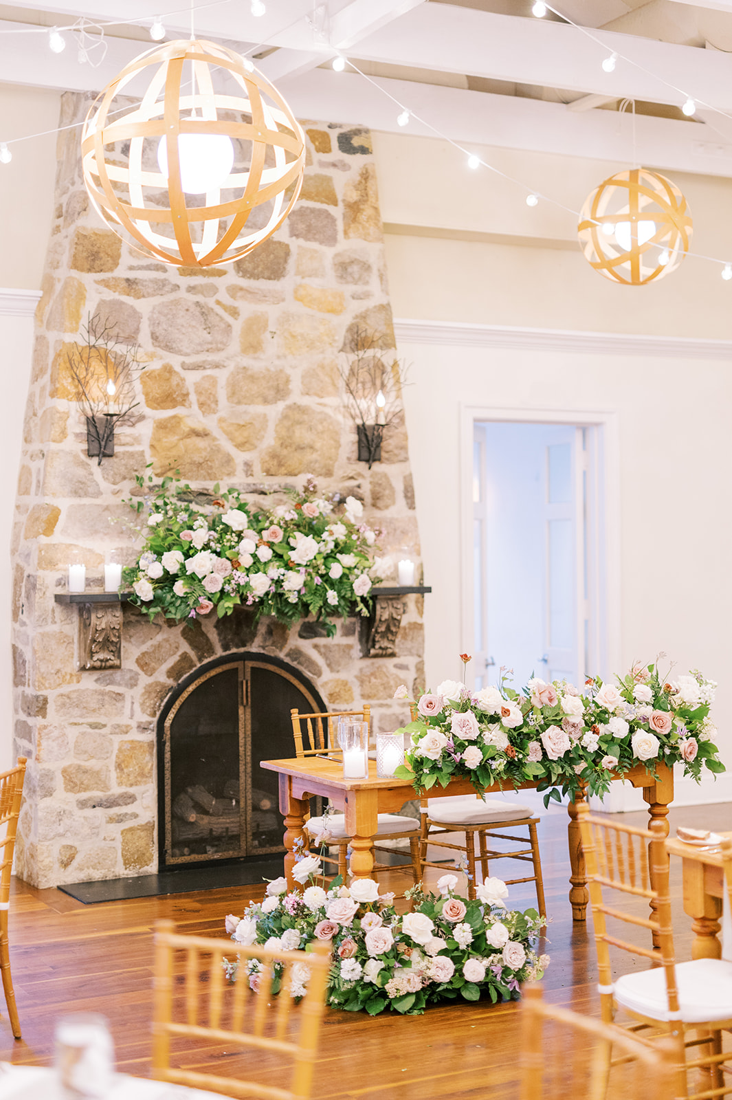 head table set up in front of stone fireplace at Pomme Radnor with parisian floral arrangements