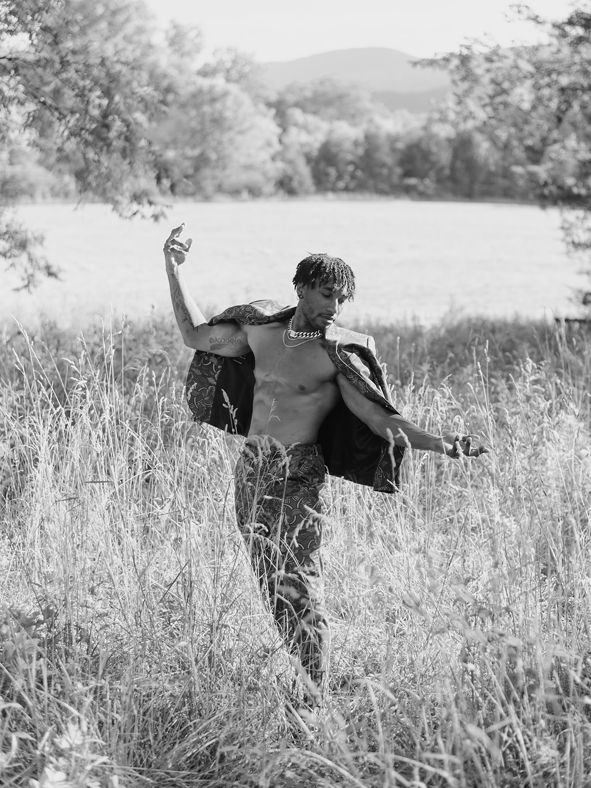 editorial photoshoot featuring a male model in a striking muted floral suit, baring his fit physique amidst nature's can