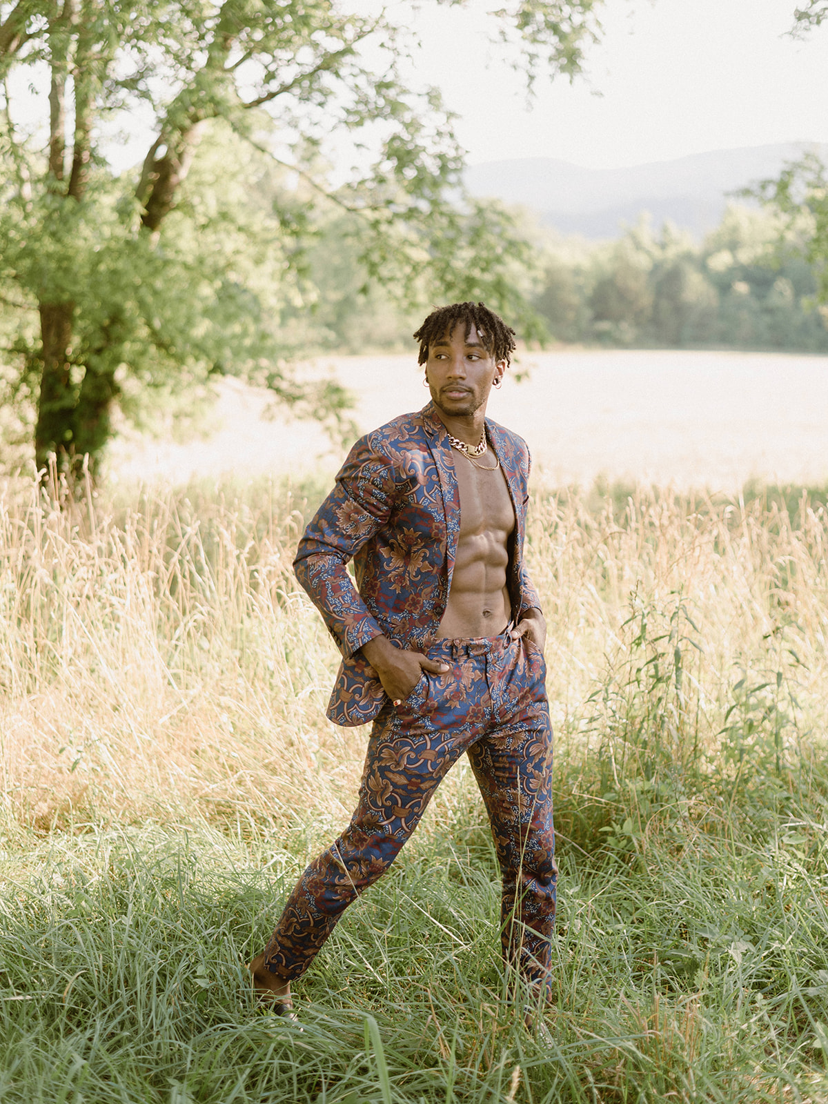 editorial photoshoot featuring a male model in a striking muted floral suit, baring his fit physique amidst nature's can