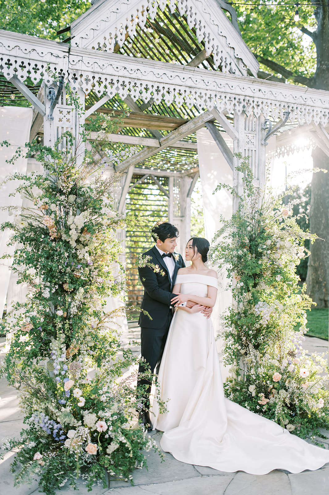 chic romantic wedding couple embrace at boho altar with wild lush floral arrangement at terrain at styers glen mills
