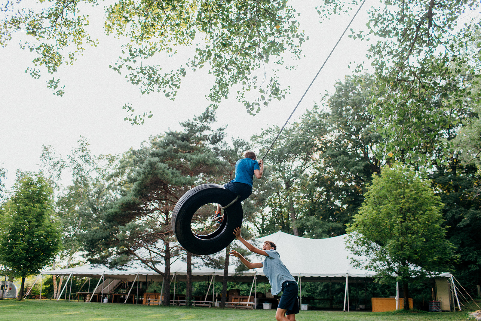 Brothers swinging each other on a tire swing at Camp Wandawega during a wedding weekend