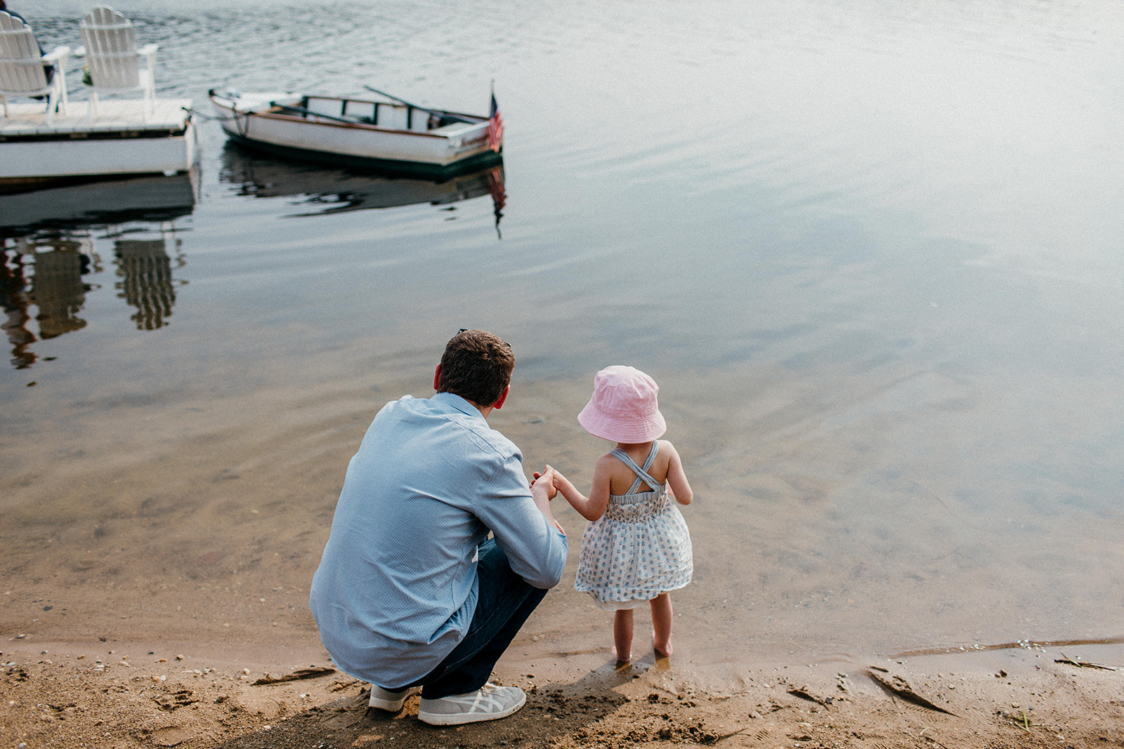A dad and his daughter throw some stones into Camp Wandawega's lake during a wedding weekend