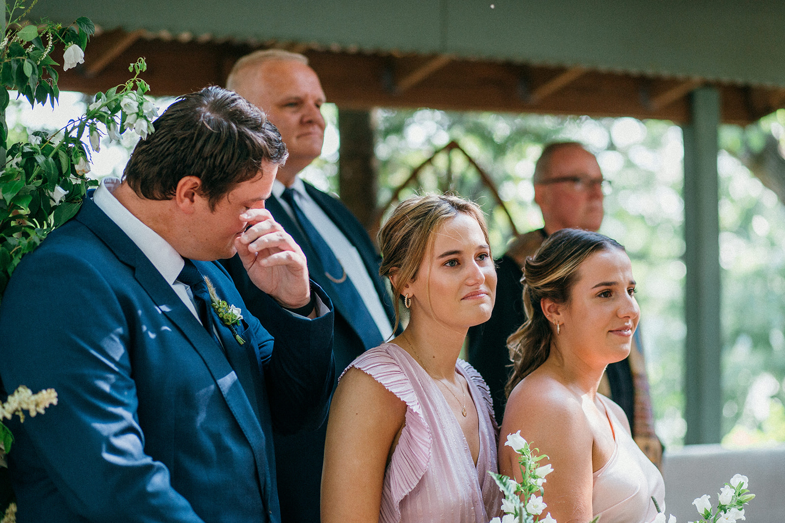 Siblings of the bride cry as their sister walks down the aisle in the chapel at Camp Wandawega