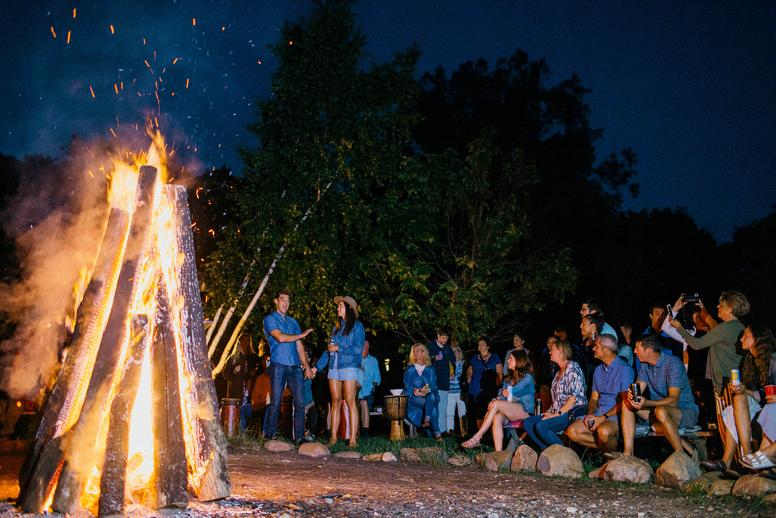 Wedding group gathers around a blazing fire at Camp Wandawega under a moonlit sky