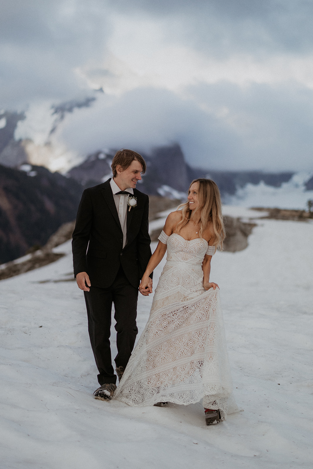 A bride and groom eloping at North Cascades National Park holding hands and walking through the snow.