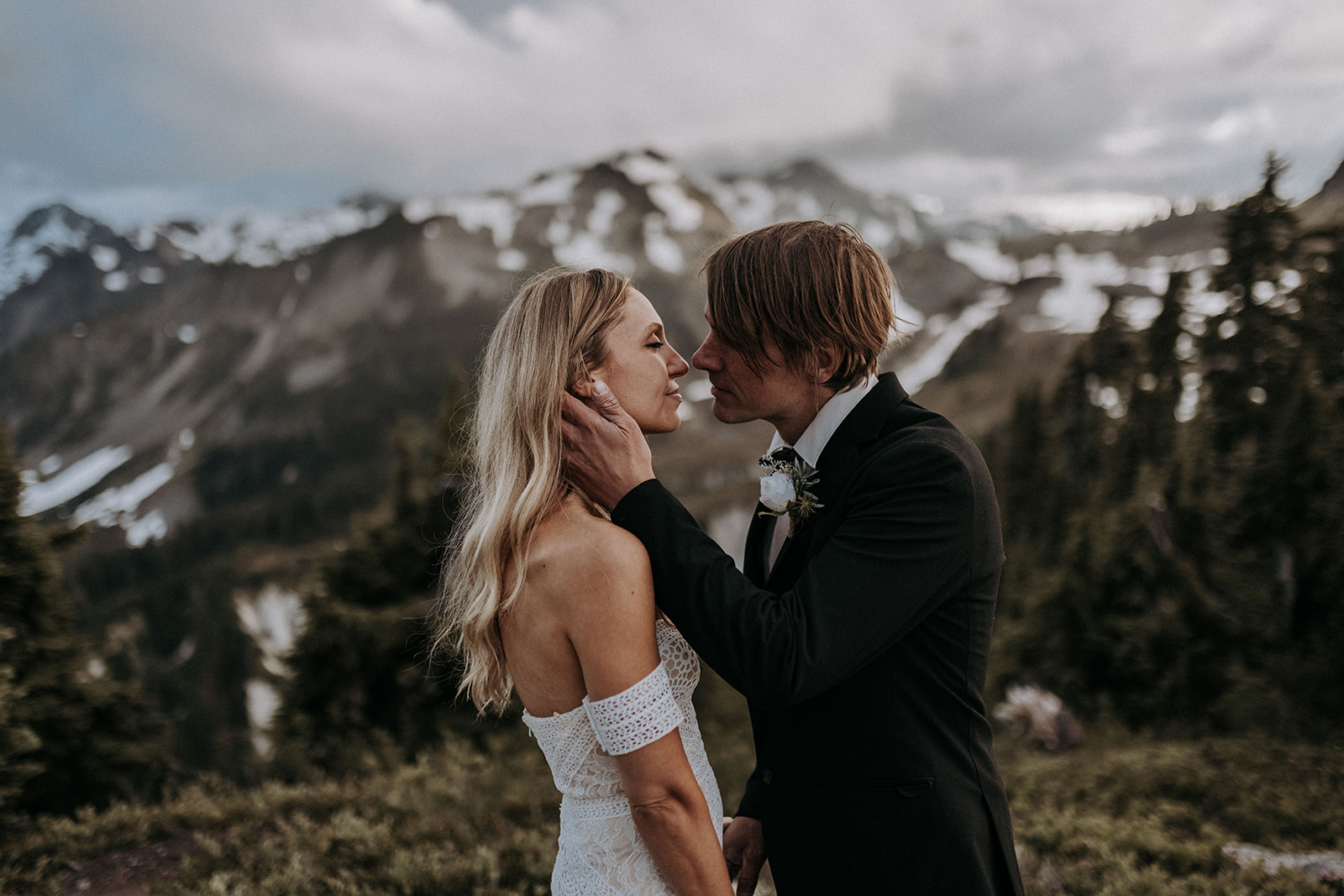 A groom cupping his bride's face and pulling her in for a kiss during their North Cascades elopement.