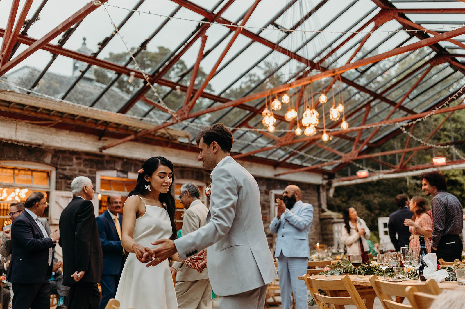 bride and groom dance in glass roofed reception at wedding