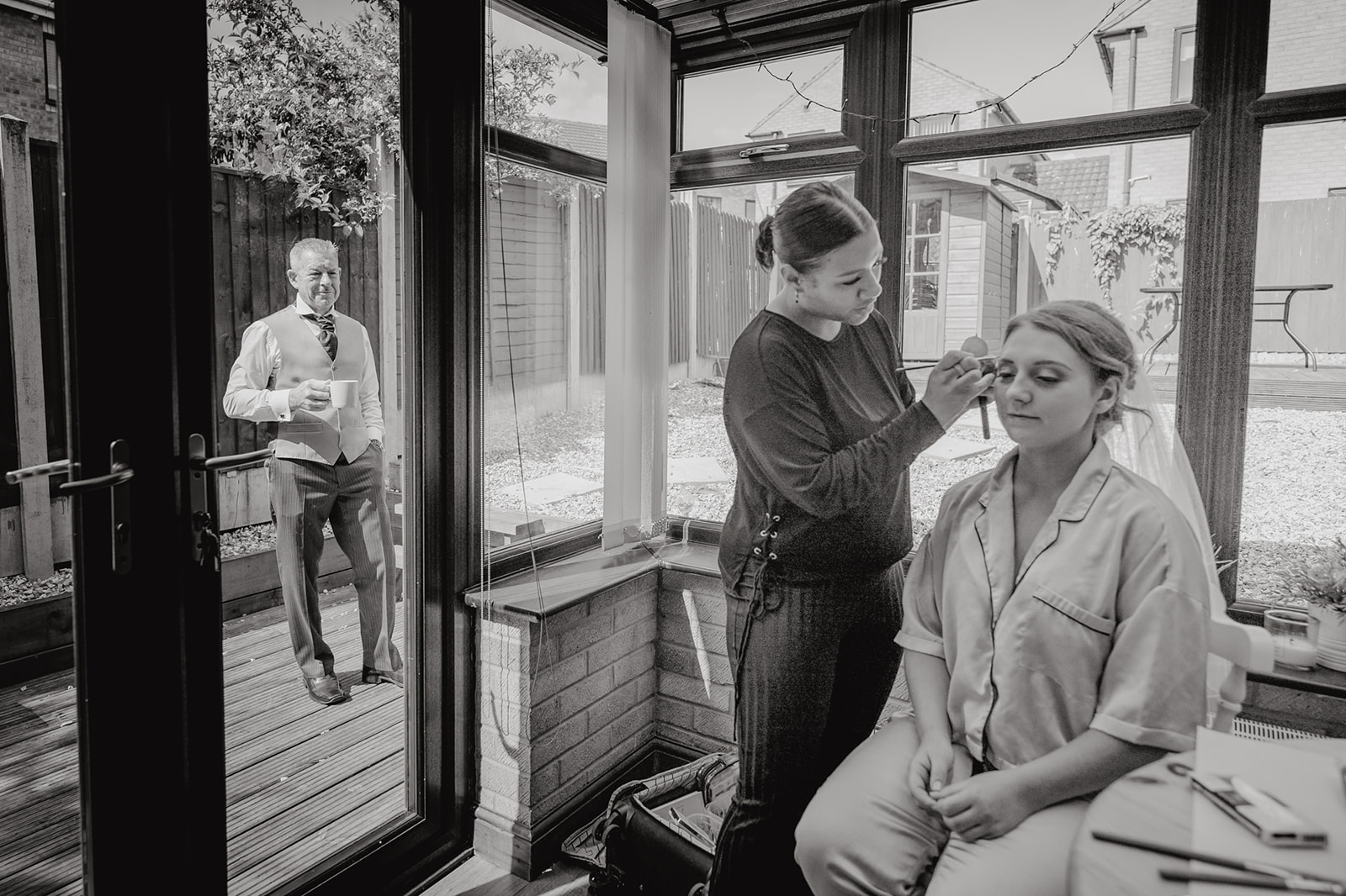  The father of the bride watching on as his daughter has her make up done on the morning of her wedding