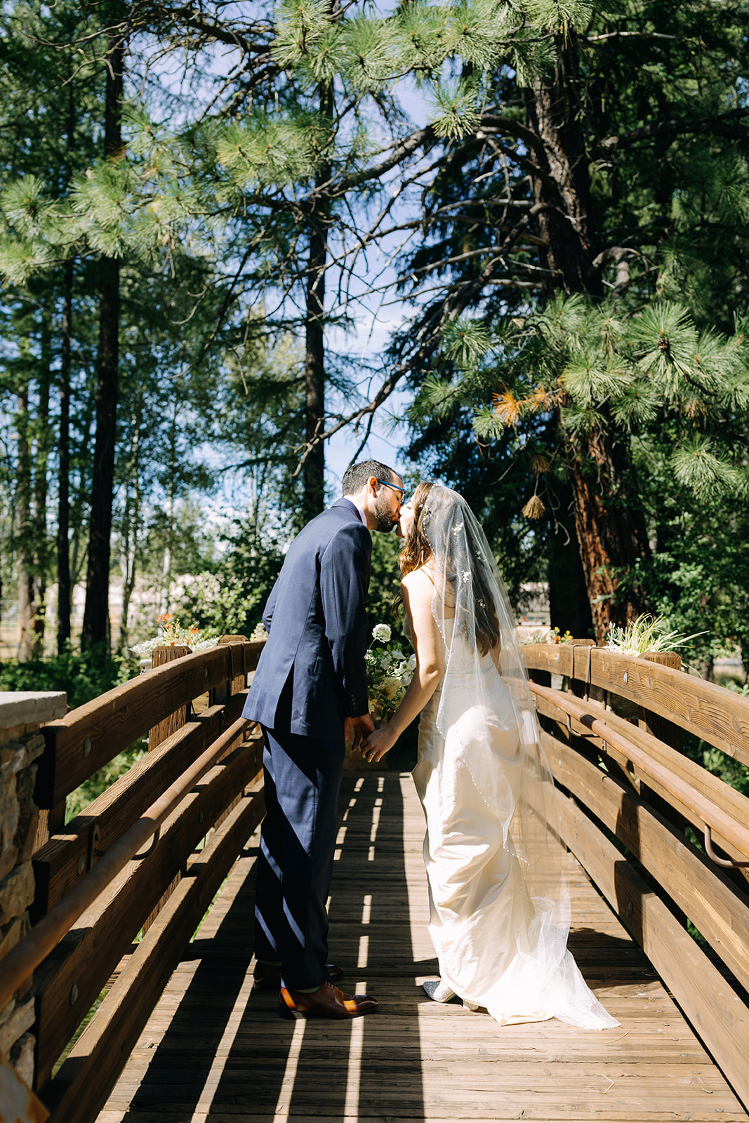 bride and groom kissing on bridge at bride and groom couples portraits at lake creek lodge