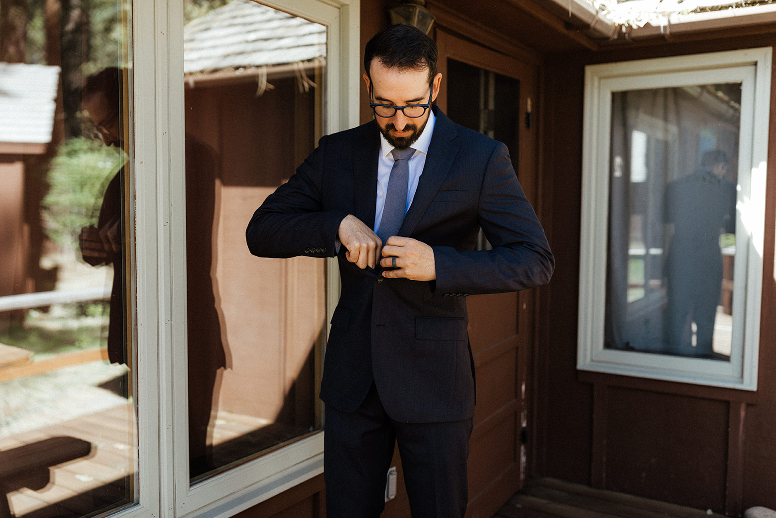 groom buttoning up his suit outside