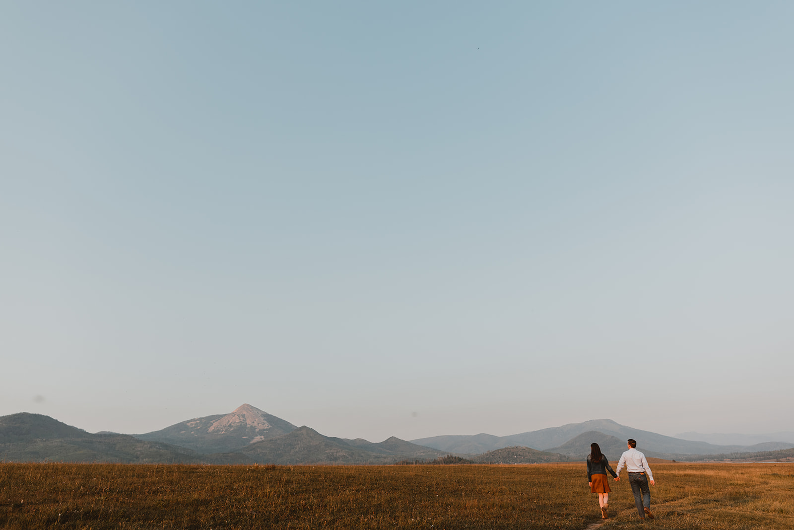 couple sits in the grass below giant mountains in steamboat springs, co 