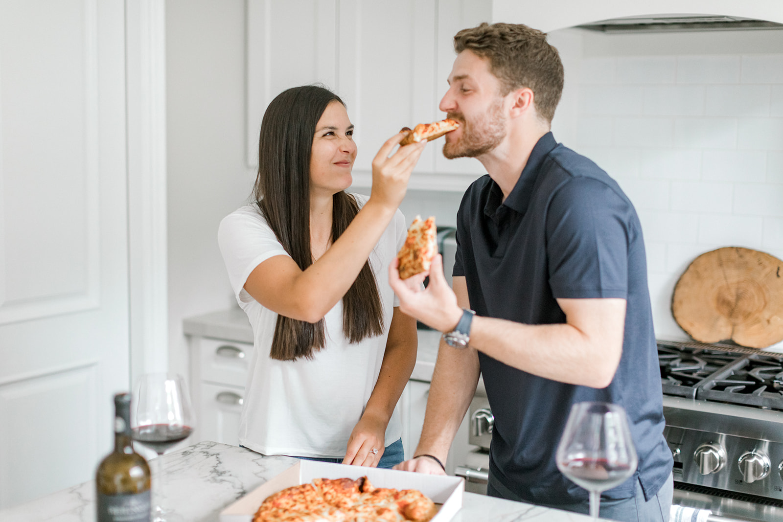 Couple shares a bite of pizza during their at-home engagement session