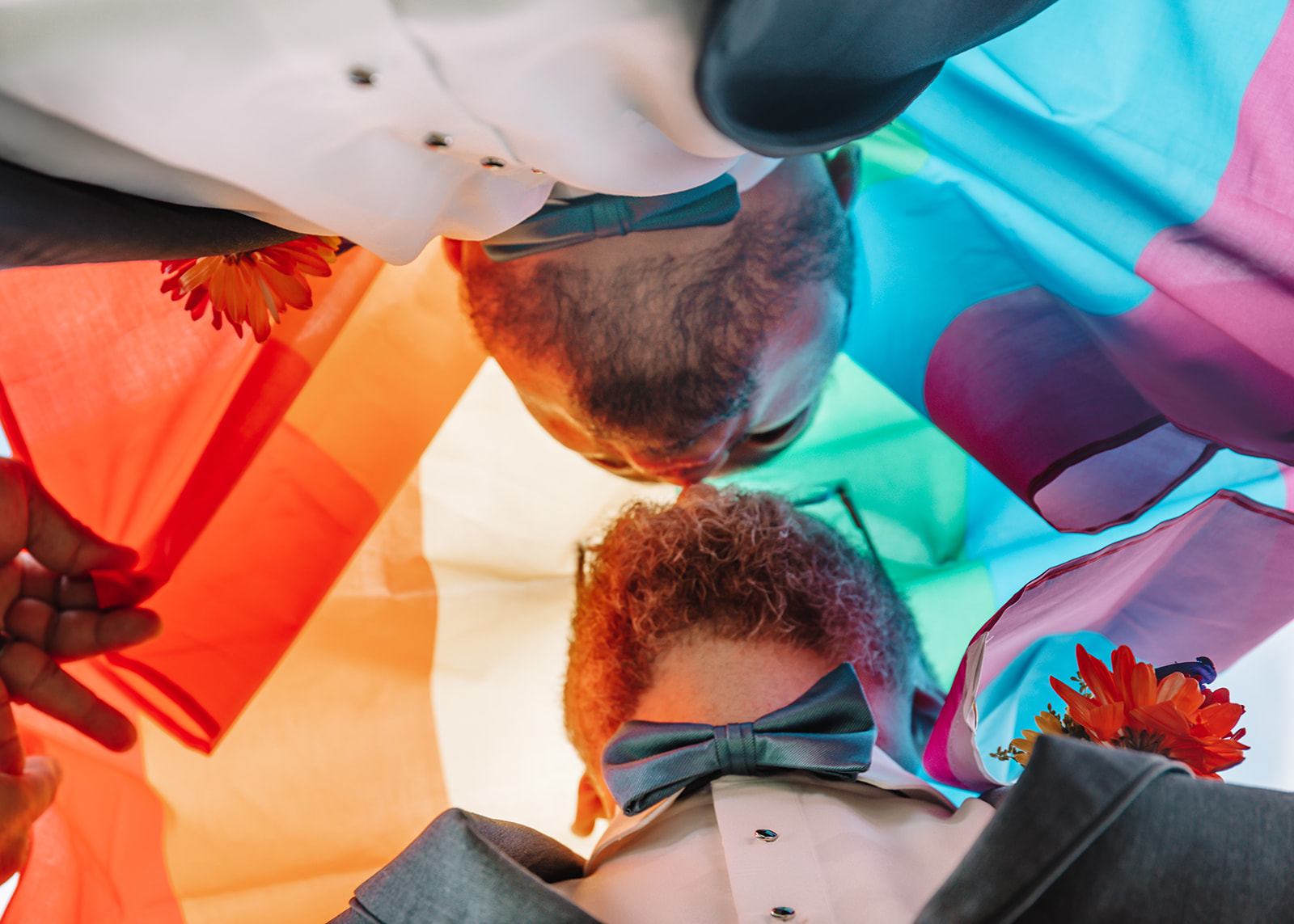 Two grooms celebrating their love under a Pride Flag. Love is love.