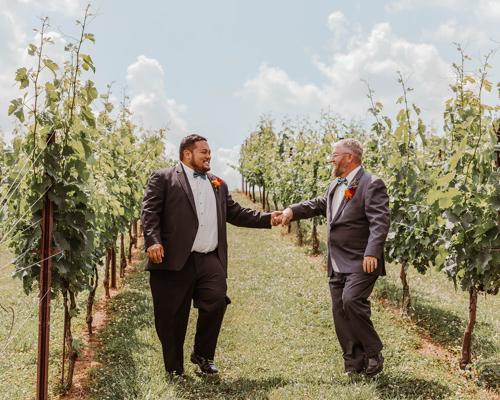 Two grooms walking through a vineyard in the southeast. 