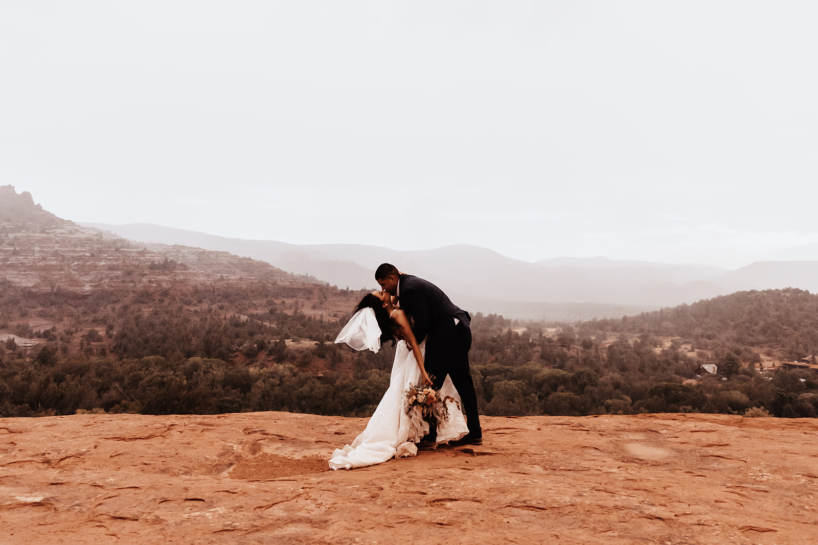 A couple who eloped in sedona dip and kiss in the rain