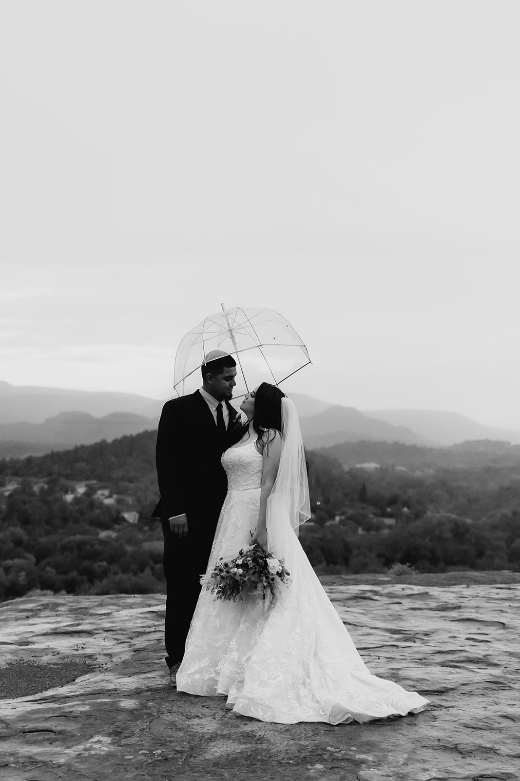 A couple who eloped in sedona kiss in the rain under an umbrella