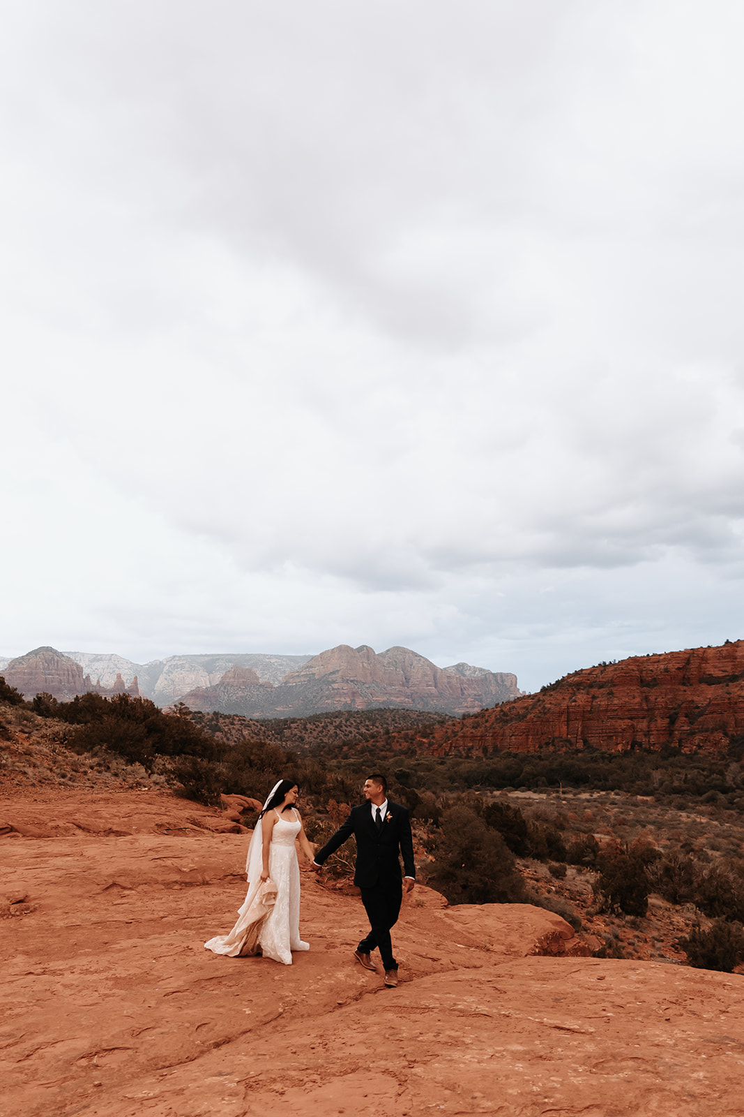 A couple who eloped in sedona walking across the red rocks