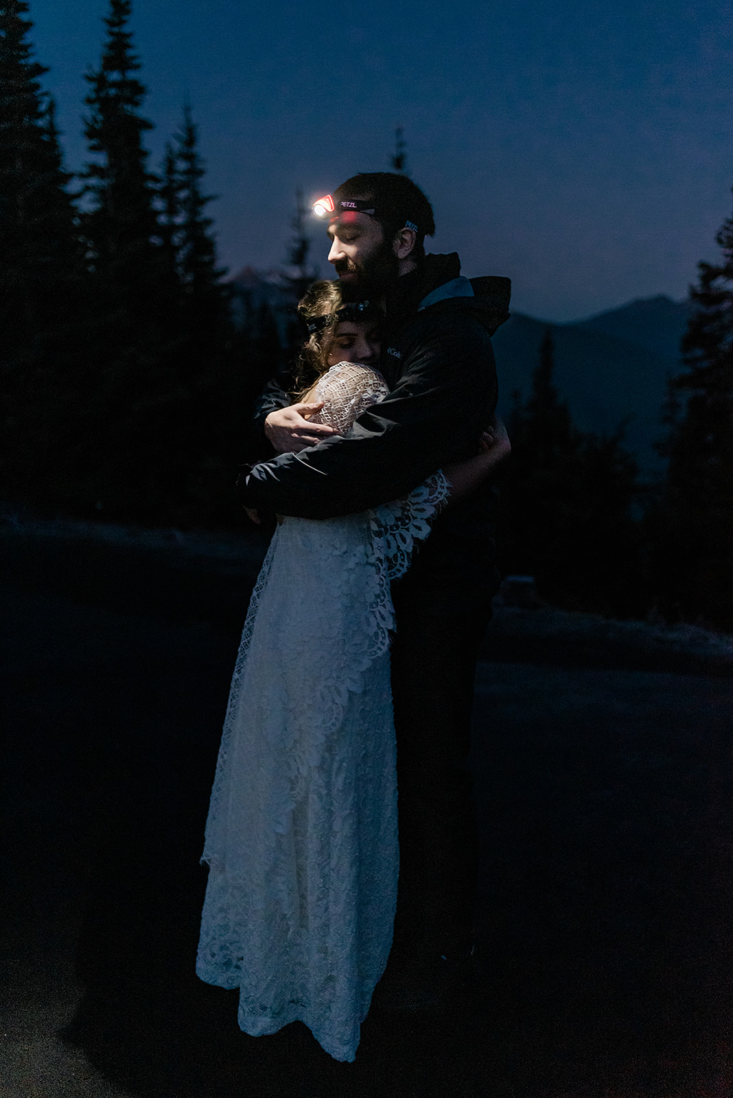 This is a couple on their wedding day before the sun has risen. They are hugging.