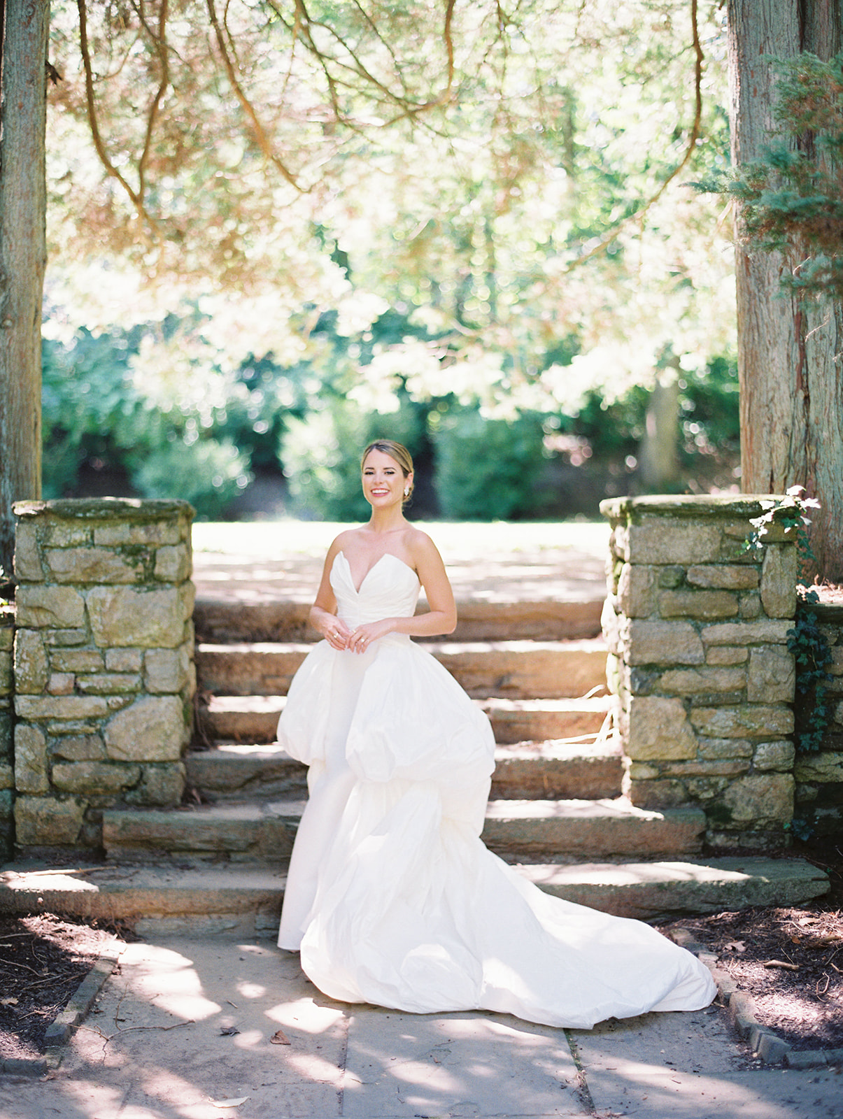 bride in couture gown stands in the garden at Timeless Summer Wedding at Parque at Historic Hunting Hill Mansion