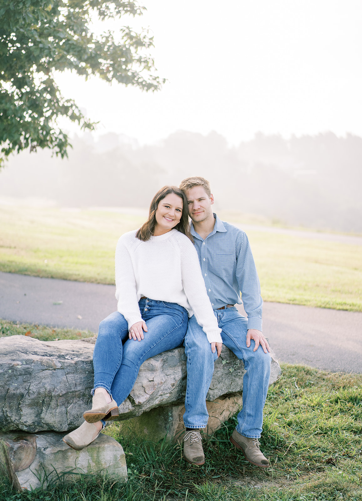 An engaged couple poses on a rock at Weathington Park, in Section, Alabama