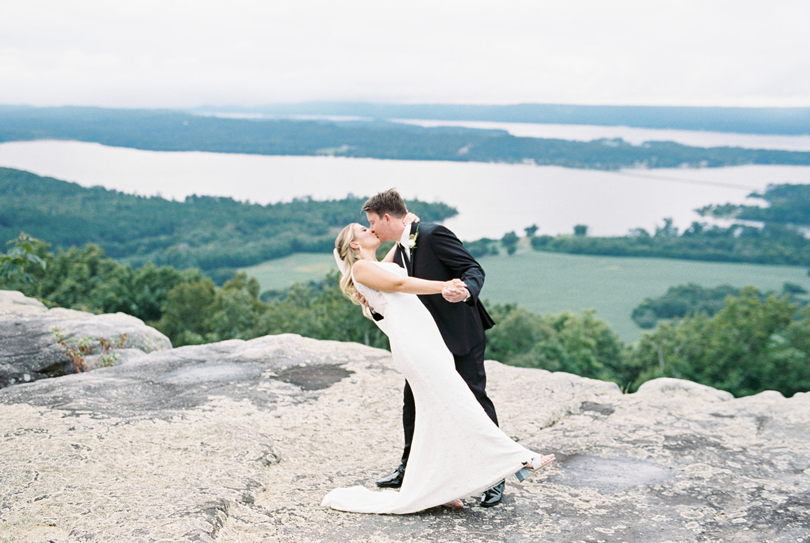 The bride and groom dip for a kiss on the bluff at Infinity Event Venue