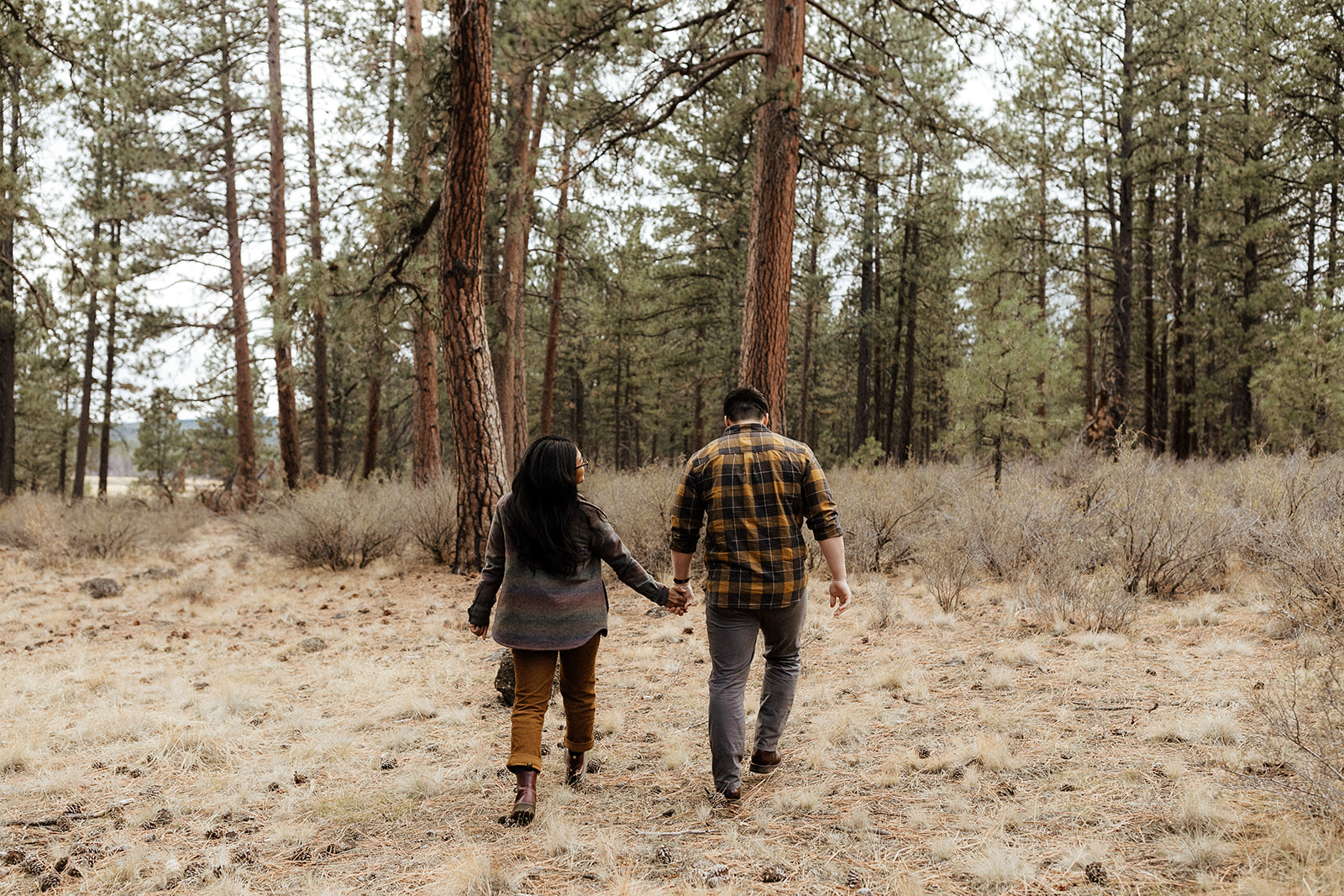 Couple walking away from the camera in the forest of Bend, Oregon at Dillon Falls.